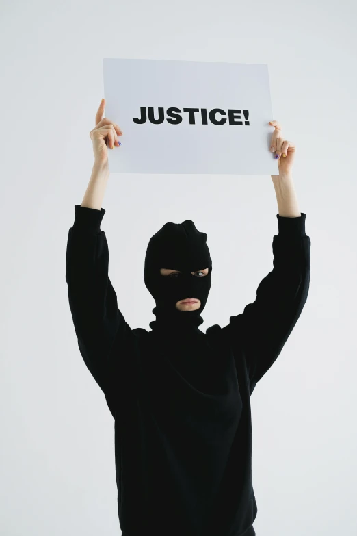 a person holding up a sign that says justice, unsplash, zentai suit, profile image, balaclava, instagram picture
