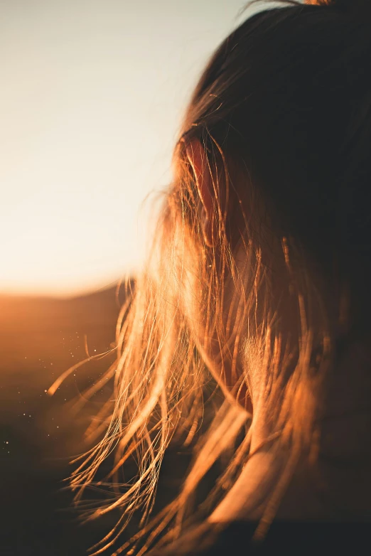 a woman with her hair blowing in the wind, trending on unsplash, sunset glow around head, grainy, close up of a blonde woman, multiple stories