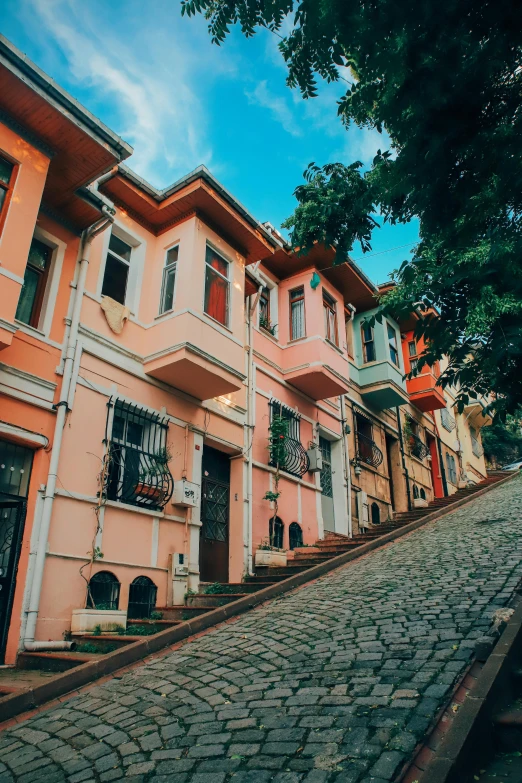 a cobblestone street in a european city, a colorized photo, by Niyazi Selimoglu, pexels contest winner, art nouveau, house on a hill, turkey, solid background, multiple colors