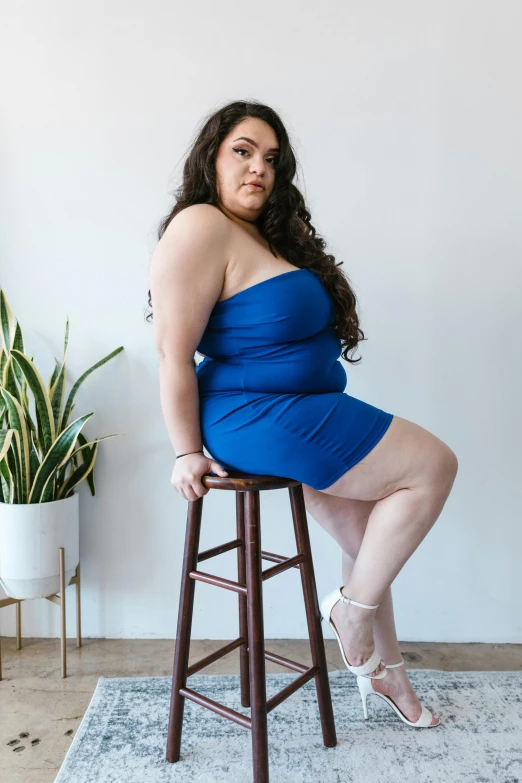 a woman in a blue dress sitting on a stool, featured on reddit, curvy model, wearing a cocktail dress, kailee mandel, promo image
