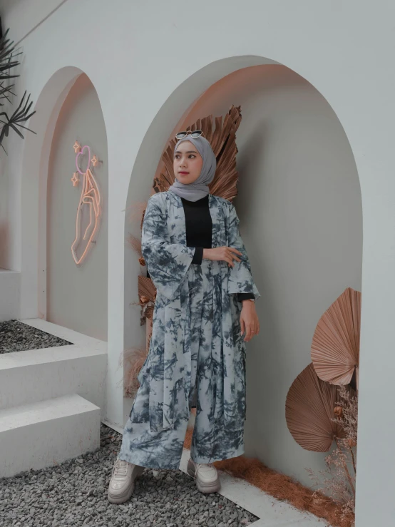 a woman standing in front of a white building, inspired by Galen Dara, instagram, dau-al-set, wearing a grey robe, batik, detailed product image, ((blue))