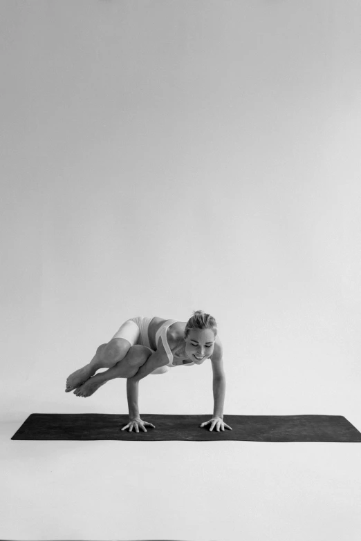 a woman doing a yoga pose on a yoga mat, a black and white photo, by Jessie Algie, ffffound, weightlessness, pose 4 of 1 6, balances