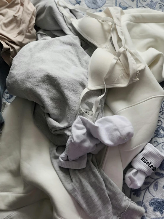 a pile of clothes sitting on top of a bed, by Matija Jama, wearing white leotard, gray hoodie, detailed product image, y2k aesthetic