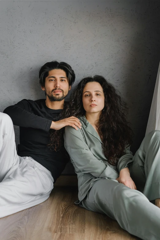 a group of people sitting on top of a wooden floor, couple on bed, grey clothes, khyzyl saleem, profile image