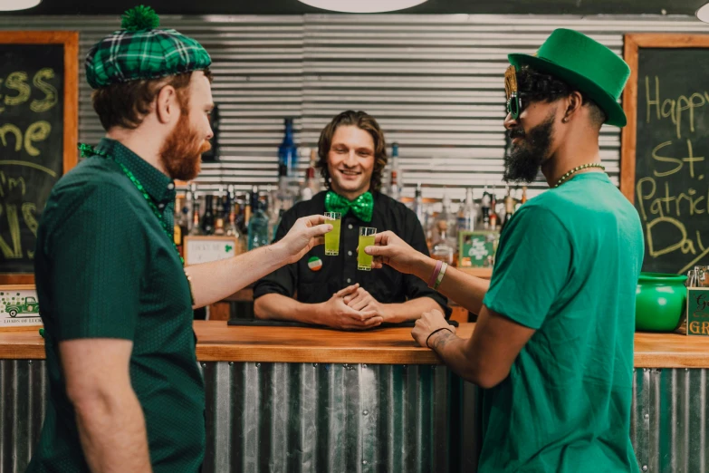 a couple of men standing next to each other at a bar, pexels contest winner, wearing green clothing, hop cone juice, lachlan bailey, green flags