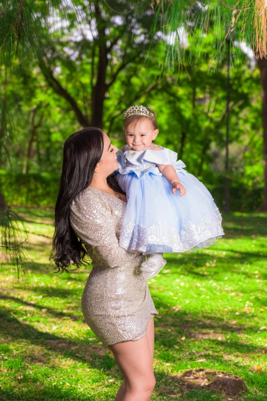 a woman holding a baby in her arms, a portrait, pixabay contest winner, wearing a light grey crown, wearing a plastic blue dress, lush surroundings, portait of haifa wehbe