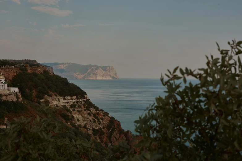 a white house sitting on top of a cliff next to the ocean, a picture, unsplash contest winner, renaissance, eucalyptus, late summer evening, profile image, maxim shirkov