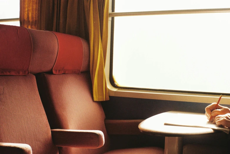 a child sitting on a train looking out the window, inspired by Wes Anderson, unsplash, romanticism, armchairs, faded red and yelow, picard on a starboard, eurostar