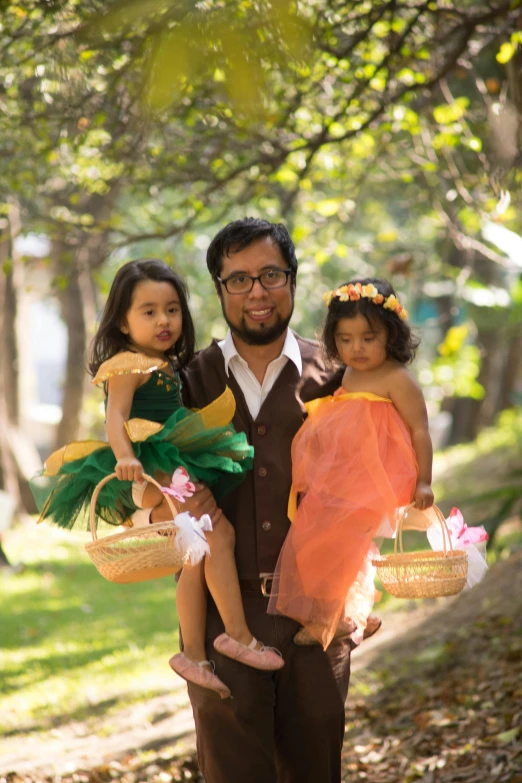 a man holding two little girls in a park, inspired by Kate Greenaway, hurufiyya, wearing cave man clothes, production photo, nivanh chanthara, with an easter basket