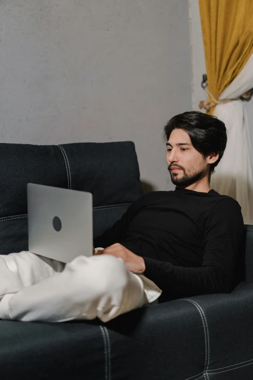 a man sitting on a couch using a laptop, pexels contest winner, renaissance, an afghan male type, ( ( theatrical ) ), wearing business casual dress, someone in home sits in bed