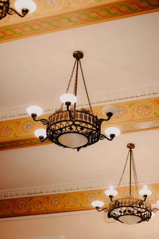 a couple of chandeliers hanging from the ceiling, inspired by Sydney Prior Hall, art nouveau, grand library, electrical details, accent lighting, ornate crown