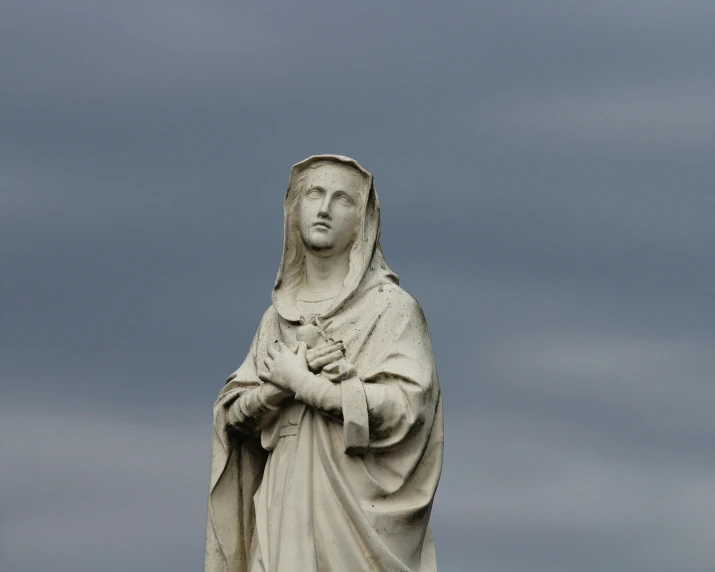 a statue of a woman on top of a building, a statue, inspired by Geertgen tot Sint Jans, pexels contest winner, figuration libre, under a gray foggy sky, her gaze is downcast, virgin mary, parce sepulto