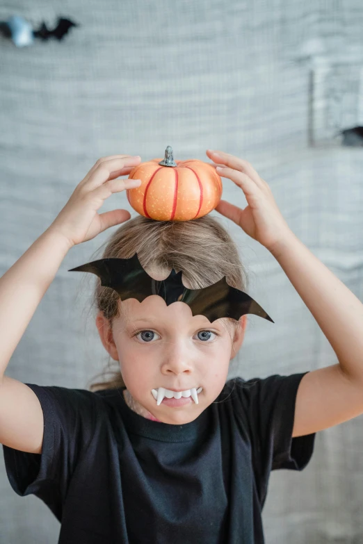 a little girl is holding a pumpkin on her head, pexels, process art, vampire bats, full product shot, wearing spiky, chalk