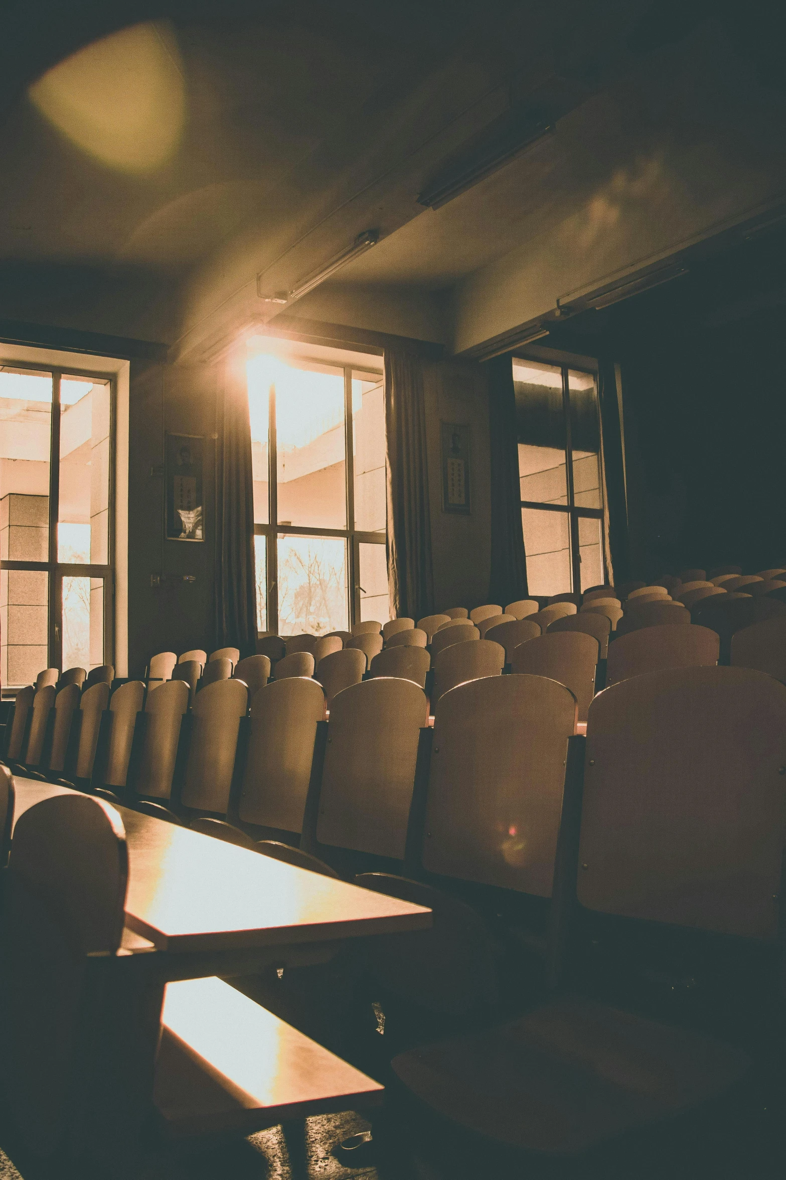 a room full of empty chairs in front of a window, happening, surrounding cinematic light, college, [ theatrical ]