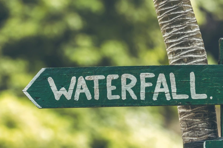 a close up of a street sign with trees in the background, waterfalls, emerald, sandfalls, thumbnail