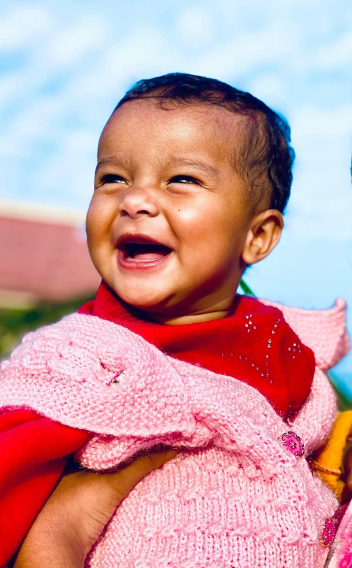 a woman holding a baby in her arms, pexels, happening, mutahar laughing, on a sunny day, vivid and detailed, pink