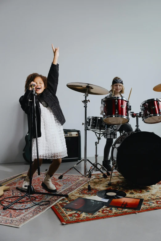 a little girl that is standing in front of a drum set, holding a microphone, bassist, promo image, rocking out