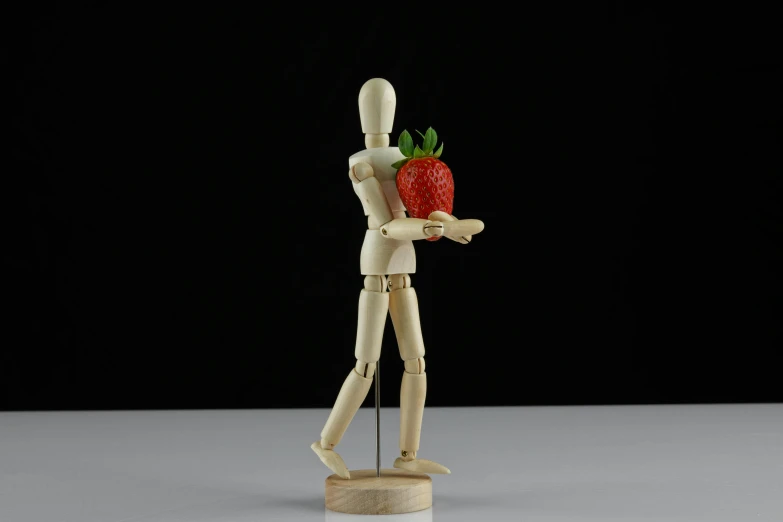 a wooden mannequin holding a strawberry in his hand, figurative art, articulated joints, illustration »