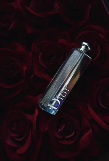 a bottle sitting on top of a bed of roses, iridescent glistening smoke, dior, blue and white and red mist, ( ( theatrical ) )