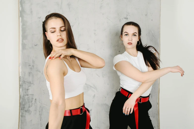 a couple of women standing next to each other, trending on pexels, arabesque, choreographed, black red white clothes, dressed in a white t-shirt, bella poarch