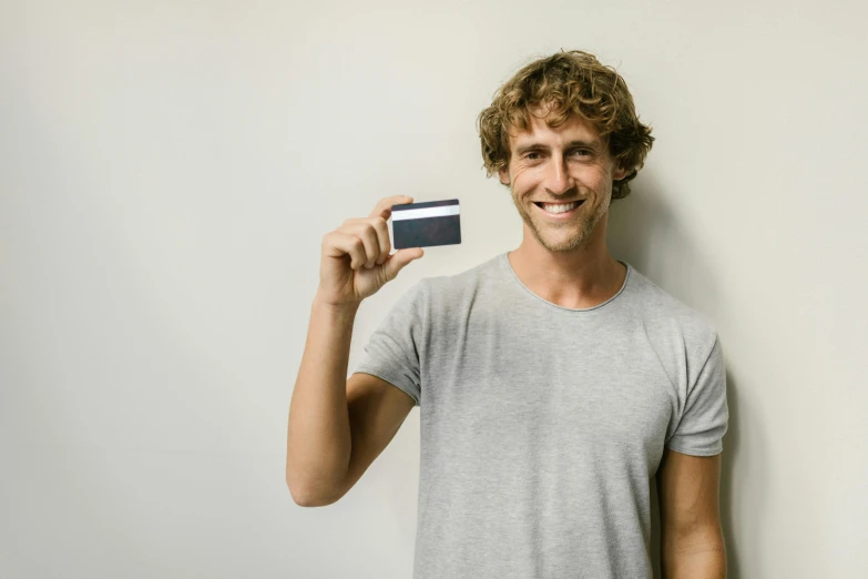 a man holding a credit card in his hand, a polaroid photo, by Matthias Stom, pexels contest winner, renaissance, skinny caucasian man, aussie, short stubble, with a long
