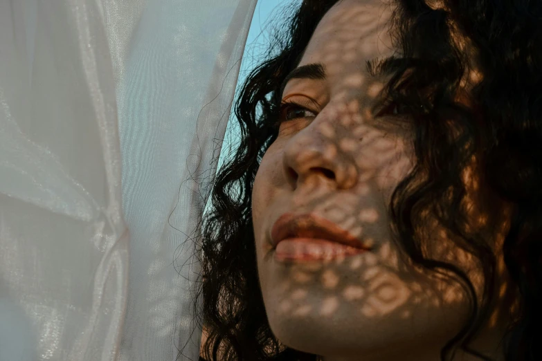 a close up of a person with long hair, pexels contest winner, middle eastern skin, the sun reflecting on a window, her face framed with curls, faces covered in shadows