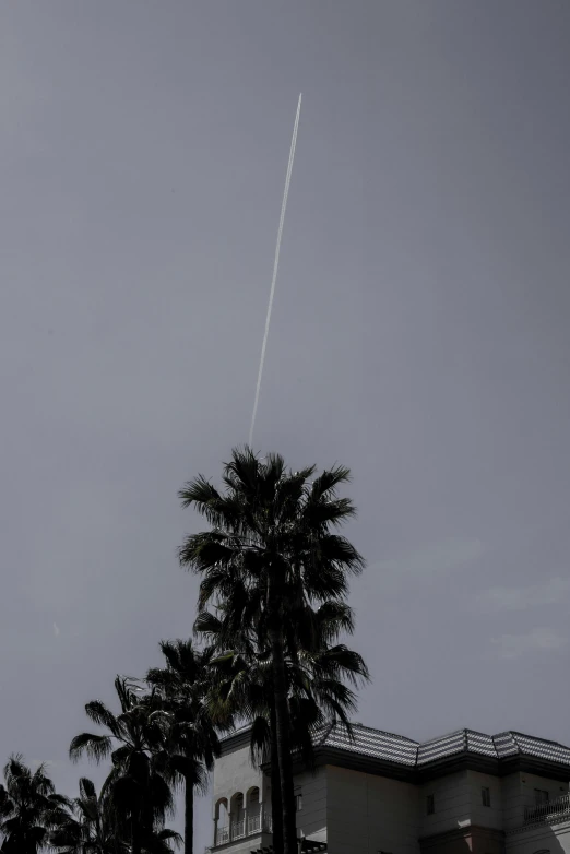a black and white photo of a plane in the sky, by Lee Loughridge, postminimalism, palm springs, meteor, taken in the late 2010s, near the beach