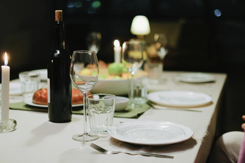 a wine bottle sitting on top of a table next to a wine glass, pexels contest winner, dinner table, family dinner, rectangle, white