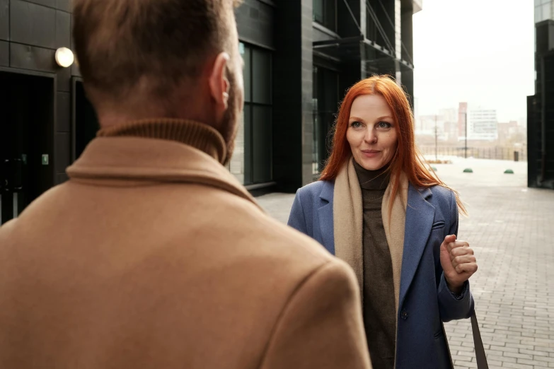 a man and a woman walking down a street, a portrait, pexels contest winner, redhead woman, calmly conversing 8k, wearing a turtleneck and jacket, people at work