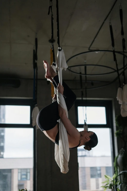 a man flying through the air on a hammock, by Jessie Algie, arabesque, in a gym, sitting in a crane, profile image, wētā fx