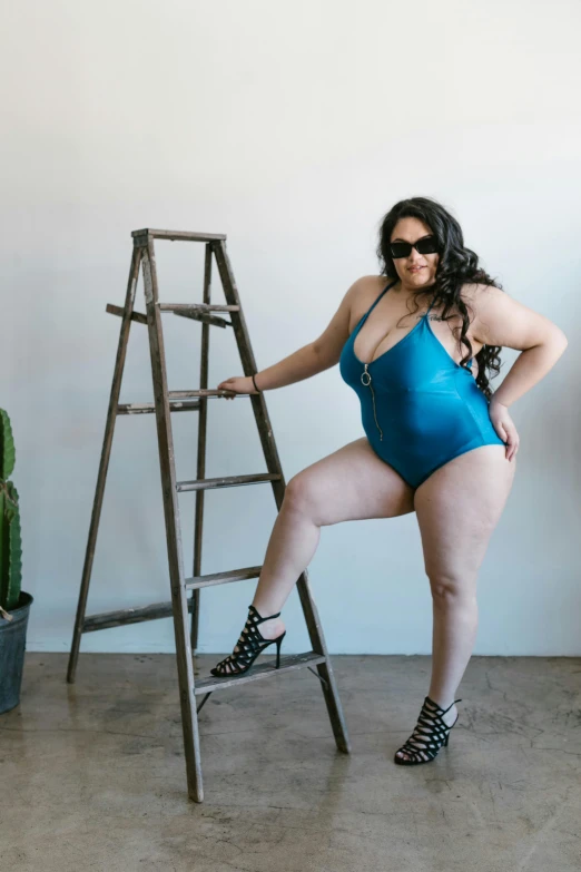 a woman in a blue swimsuit leaning on a ladder, by Winona Nelson, unsplash, alluring plus sized model, shades, full body in view, brittney lee