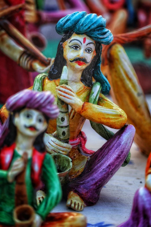 a group of figurines sitting on top of a table, an album cover, bengal school of art, holi festival of rich color, close - up on detailed, wood ornaments, made of clay