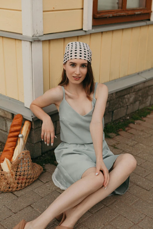 a woman sitting on the ground next to a basket of bread, inspired by Louisa Matthíasdóttir, trending on pexels, pale green halter top, bandana, soft silk dress, wearing : tanktop