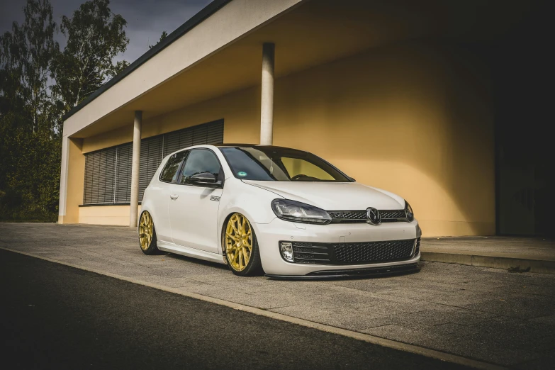 a white car parked in front of a building, pexels contest winner, baroque, wrx golf, gold and black, bunny, white wheel rims