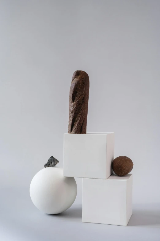 a sculpture sitting on top of a white cube, inspired by Gillis Rombouts, chocolate. rugged, soft vignette, cannonballs, medium long shot