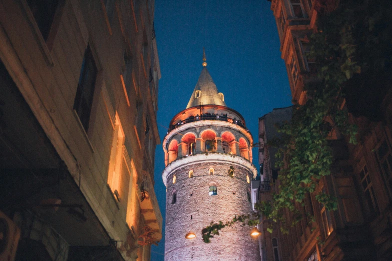 a tall tower sitting in the middle of a city, an album cover, inspired by Altoon Sultan, pexels contest winner, night light, turkey, prussian blue and venetian red, exterior view