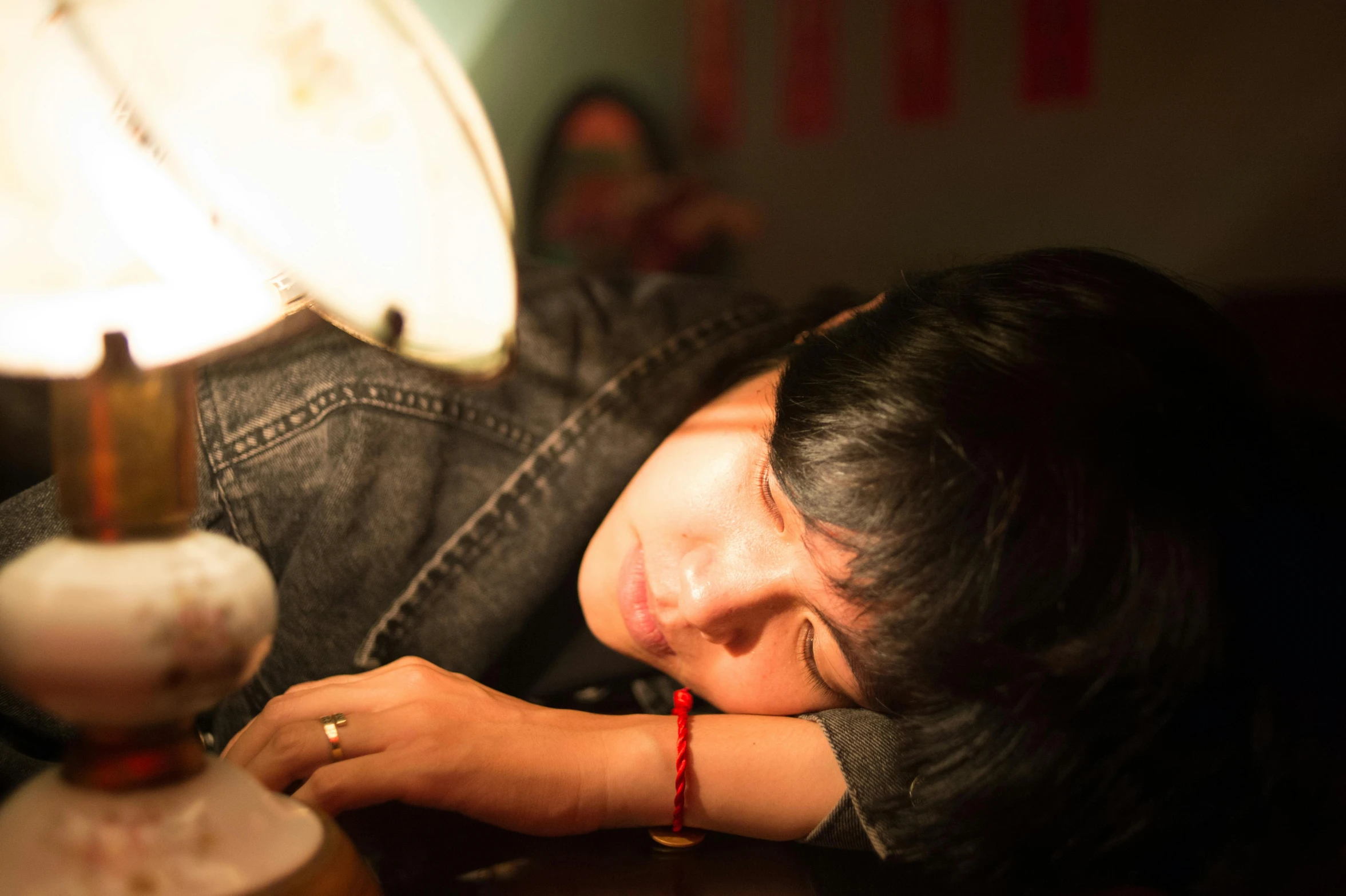 a woman laying on top of a table next to a lamp, pexels contest winner, happening, asian male, sleepy expression, profile image, student