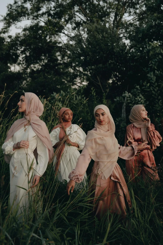 a group of women standing next to each other in a field, an album cover, by Basuki Abdullah, unsplash contest winner, hurufiyya, diverse costumes, white hijab, 5 0 0 px models, summer evening