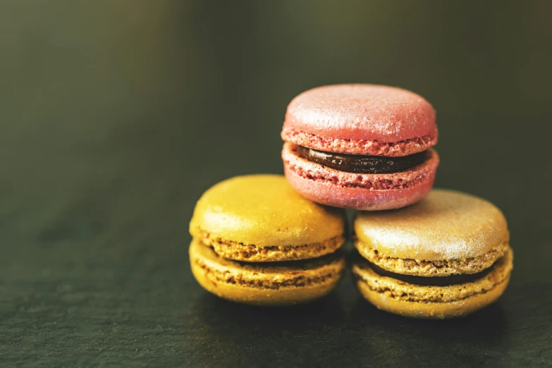 three macarons stacked on top of each other, a macro photograph, pexels, visual art, shades of aerochrome gold, thumbnail, chocolate frosting, pink and yellow