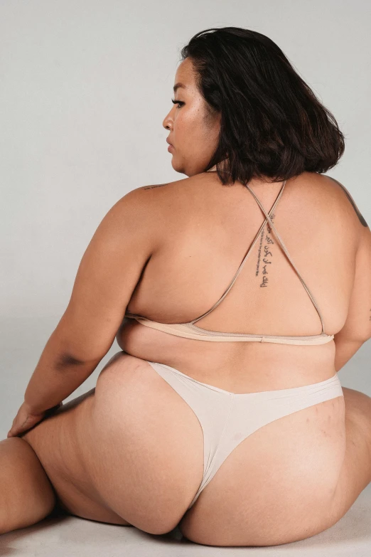 a woman in a bikini sitting on the floor, unsplash, renaissance, standing with her back to us, bbwchan, non binary model, light tan