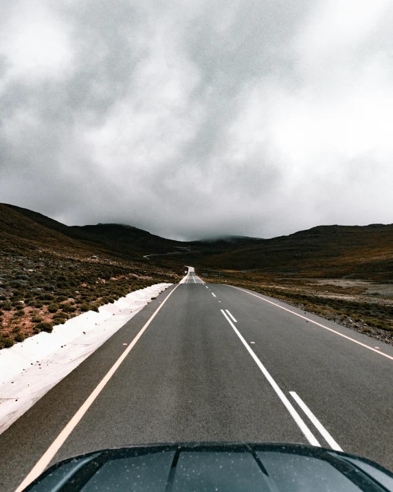 a car driving down a road on a cloudy day, an album cover, trending on unsplash, andes, multiple stories, tourist photo, 🚿🗝📝