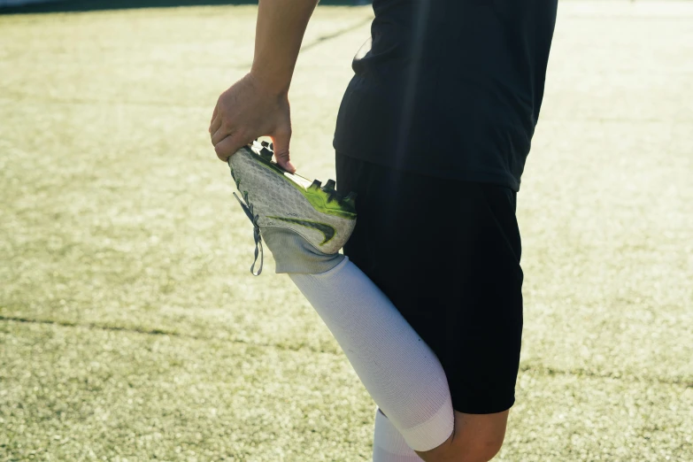 a woman standing on top of a tennis court holding a tennis racquet, a picture, by Tom Bonson, pexels, renaissance, stretching her legs on the grass, on a football field, young man with short, white leggings