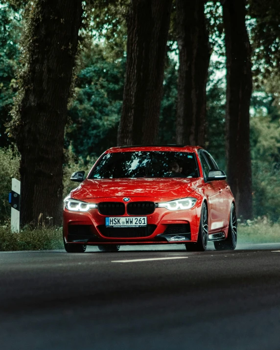 a red bmw car driving down a road, by Adam Marczyński, pexels contest winner, black forest, square, front flash, gif