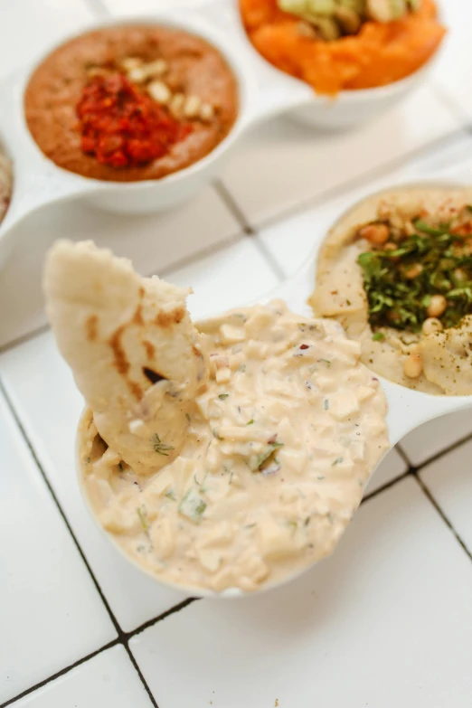 a table topped with bowls of different types of dips, dau-al-set, multiple details, cream, uncropped, ameera al taweel