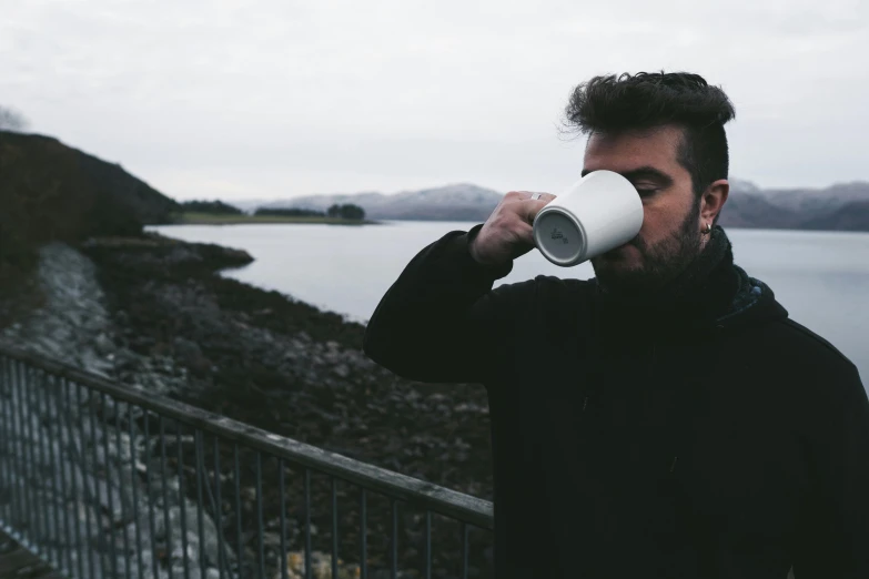 a man drinking out of a coffee cup, by Hallsteinn Sigurðsson, happening, shoreline, grey, riyahd cassiem, skye meaker