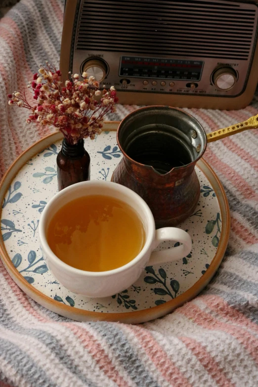 a cup of tea on a plate next to an old radio, dau-al-set, cozy bed, drinking cough syrup, botanicals, trending photo