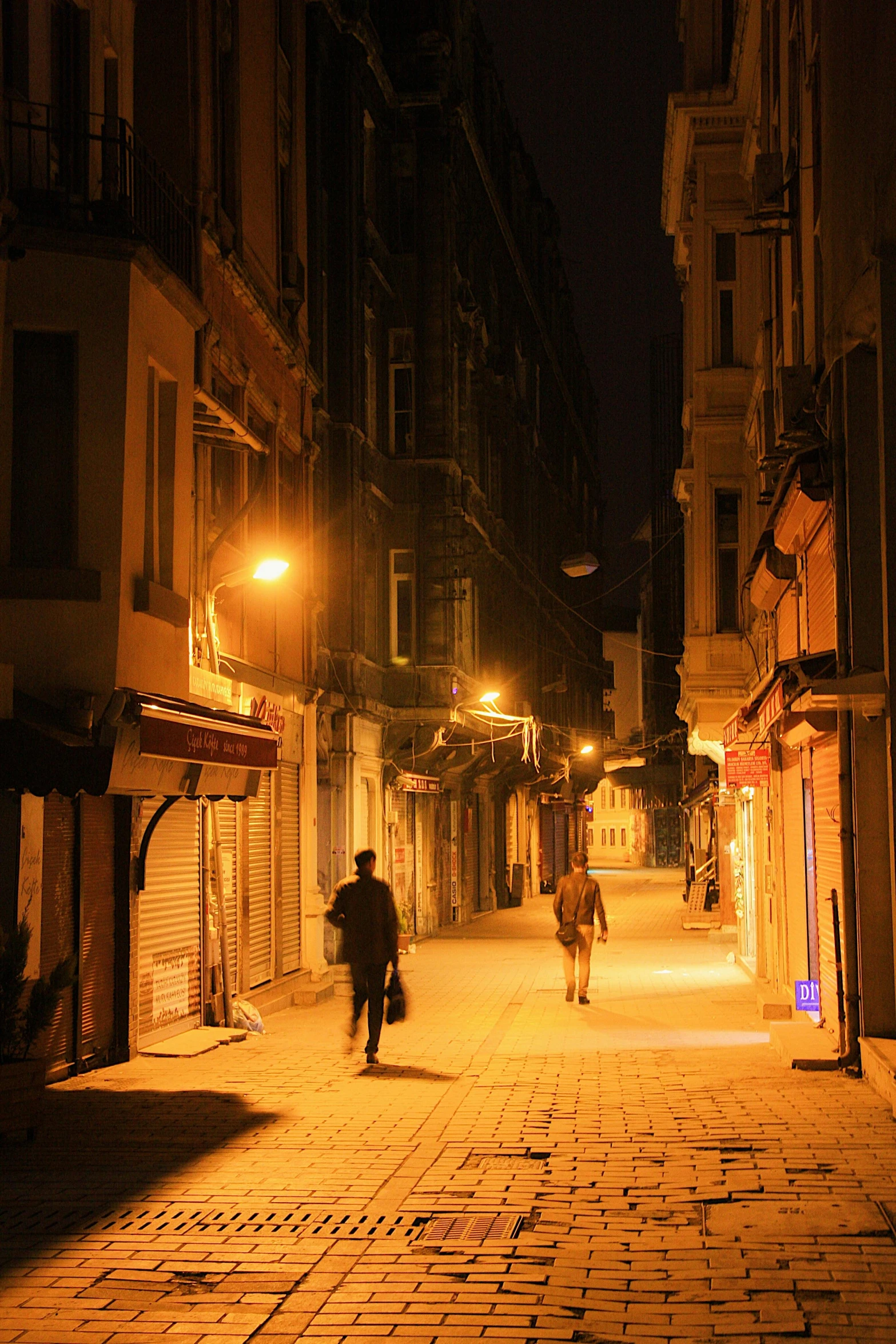 a couple of people walking down a street at night, istanbul, completely empty, venice, late morning