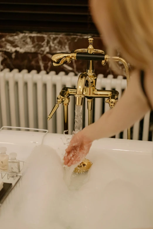 a woman washing her hands in a bathtub, a marble sculpture, by Julia Pishtar, unsplash, gold plated, low quality footage, edwardian, gilt metal