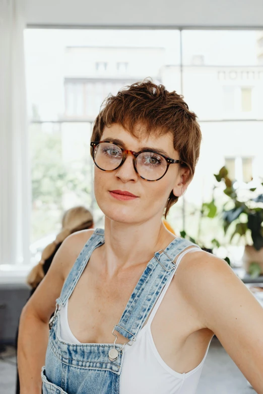 a woman sitting on a couch in a living room, inspired by Louisa Matthíasdóttir, pexels contest winner, with nerdy glasses and goatee, pixie cut, artist wearing overalls, headshot profile picture