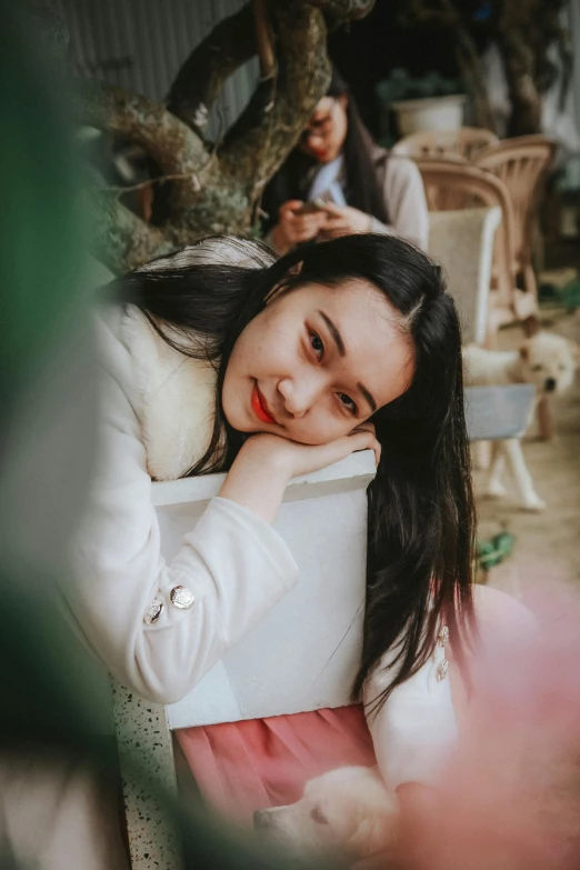 a woman sitting on top of a chair next to a tree, by Tan Ting-pho, pexels contest winner, realism, young cute wan asian face, resting head on hands, high angle closeup portrait, smiling sweetly